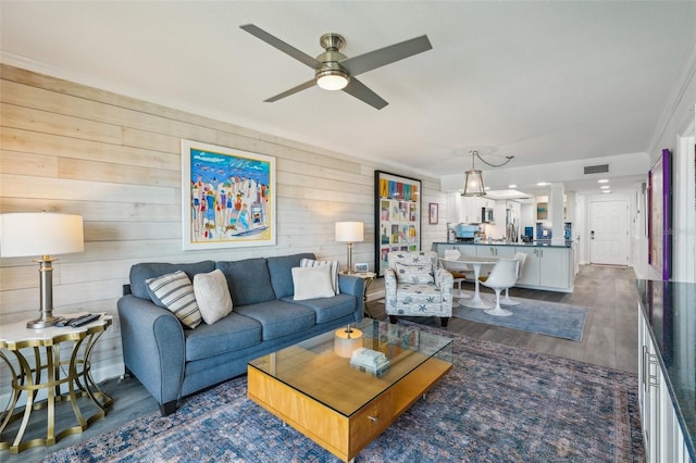 7564 Bayshore Dr Unit 302, Treasure Island, FL 33706 - living area featuring dark wood-style flooring, a ceiling fan, decorative columns, and wood walls