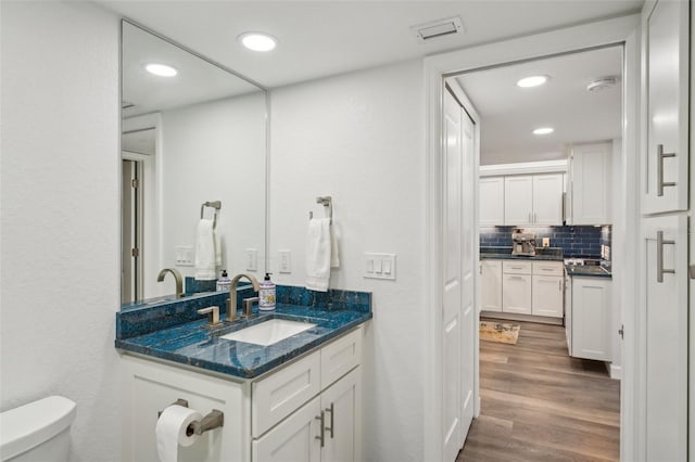 7564 Bayshore Dr Unit 302, Treasure Island, FL 33706 - bathroom featuring toilet, vanity, wood finished floors, backsplash, and recessed lighting