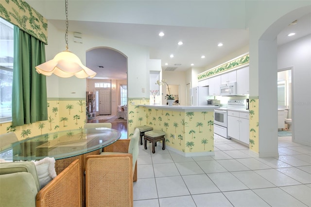 dining room with arched walkways, light tile patterned flooring, recessed lighting, and baseboards