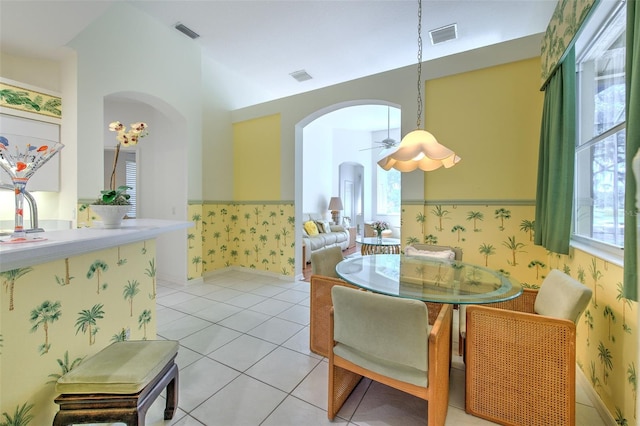 dining room with wallpapered walls, arched walkways, light tile patterned floors, and ceiling fan