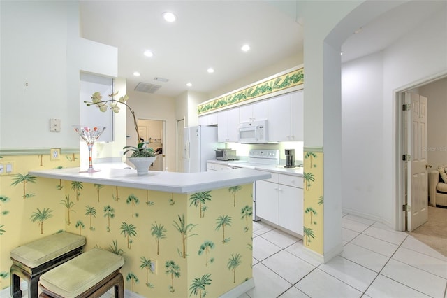 kitchen with white appliances, arched walkways, a peninsula, light countertops, and white cabinets