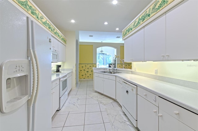 kitchen with white appliances, a sink, arched walkways, white cabinets, and light countertops
