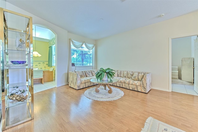 living area featuring wood finished floors, arched walkways, and baseboards