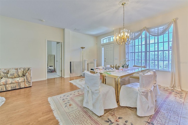 dining space featuring a chandelier, wood finished floors, and baseboards