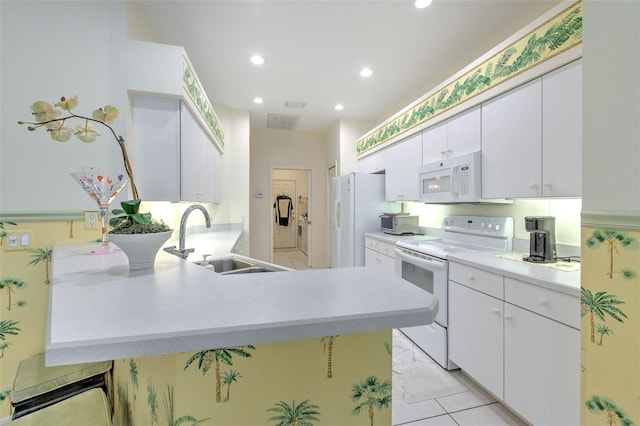 kitchen with white appliances, a sink, light countertops, white cabinets, and a peninsula