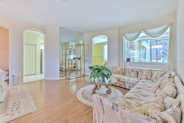 living room featuring arched walkways, wood finished floors, and baseboards