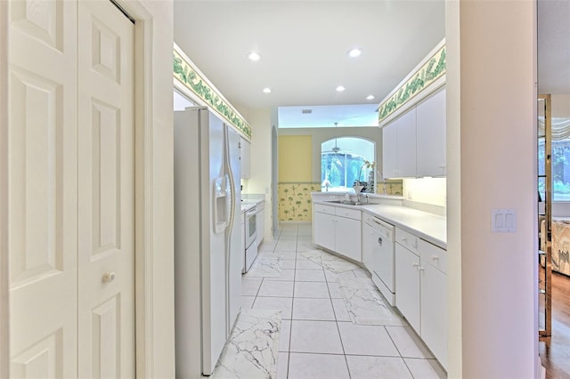 kitchen featuring white appliances, a sink, white cabinetry, light countertops, and recessed lighting
