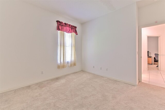unfurnished room with light carpet and baseboards