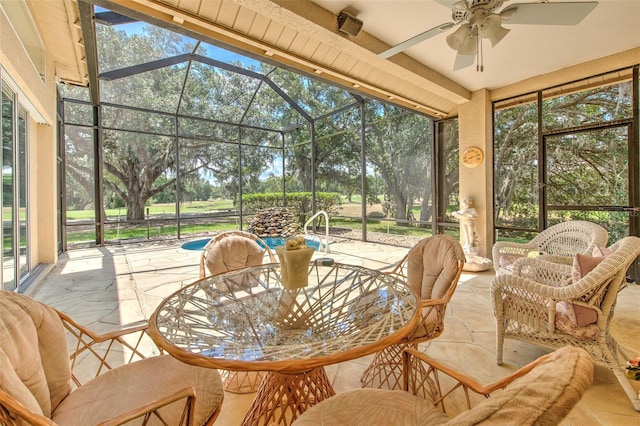 sunroom / solarium with ceiling fan, outdoor dining space, and view of scattered trees