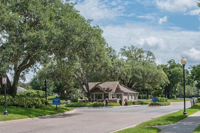 view of asphalt road with street lights, curbs, and a gated entry