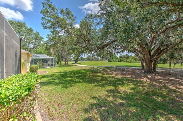 view of green lawn featuring glass enclosure
