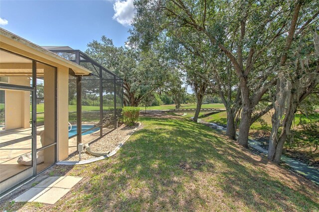 view of green lawn with an outdoor pool, a patio, and a lanai