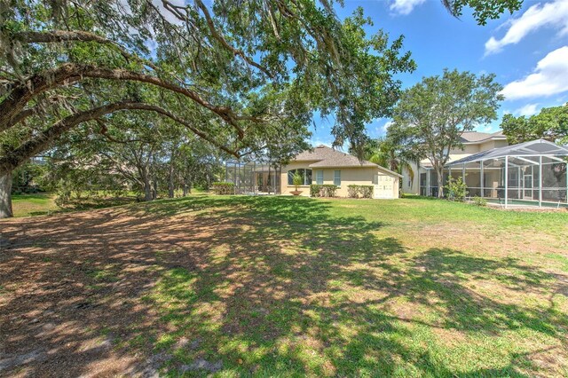 view of green lawn featuring glass enclosure