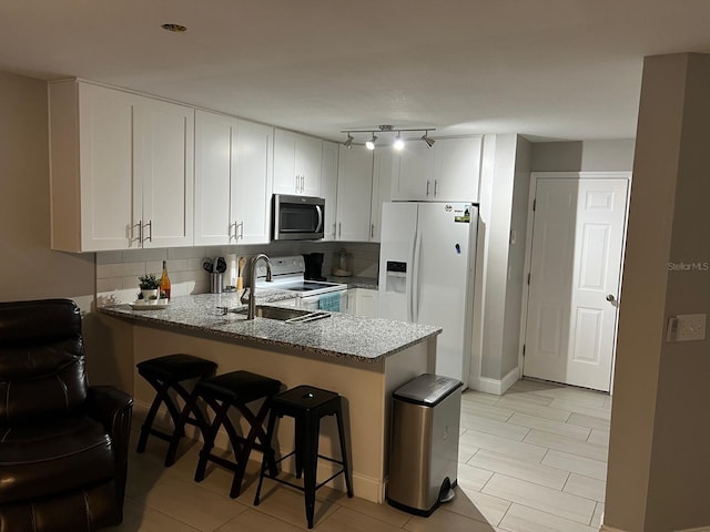 8423 Edgewater Place Blvd, Tampa, FL 33615 - kitchen featuring white appliances, a sink, light stone counters, a peninsula, and white cabinetry