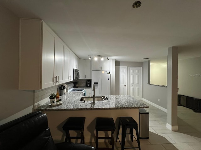 8423 Edgewater Place Blvd, Tampa, FL 33615 - kitchen featuring white appliances, a sink, a peninsula, light stone countertops, and a kitchen bar