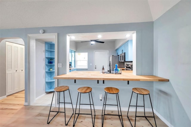 2003 Cordova Grn, Seminole, FL 33777 - kitchen featuring butcher block counters, stainless steel appliances, a peninsula, a kitchen bar, and baseboards