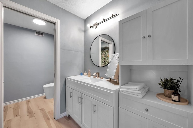 2003 Cordova Grn, Seminole, FL 33777 - bathroom with toilet, wood finished floors, vanity, a textured ceiling, and baseboards