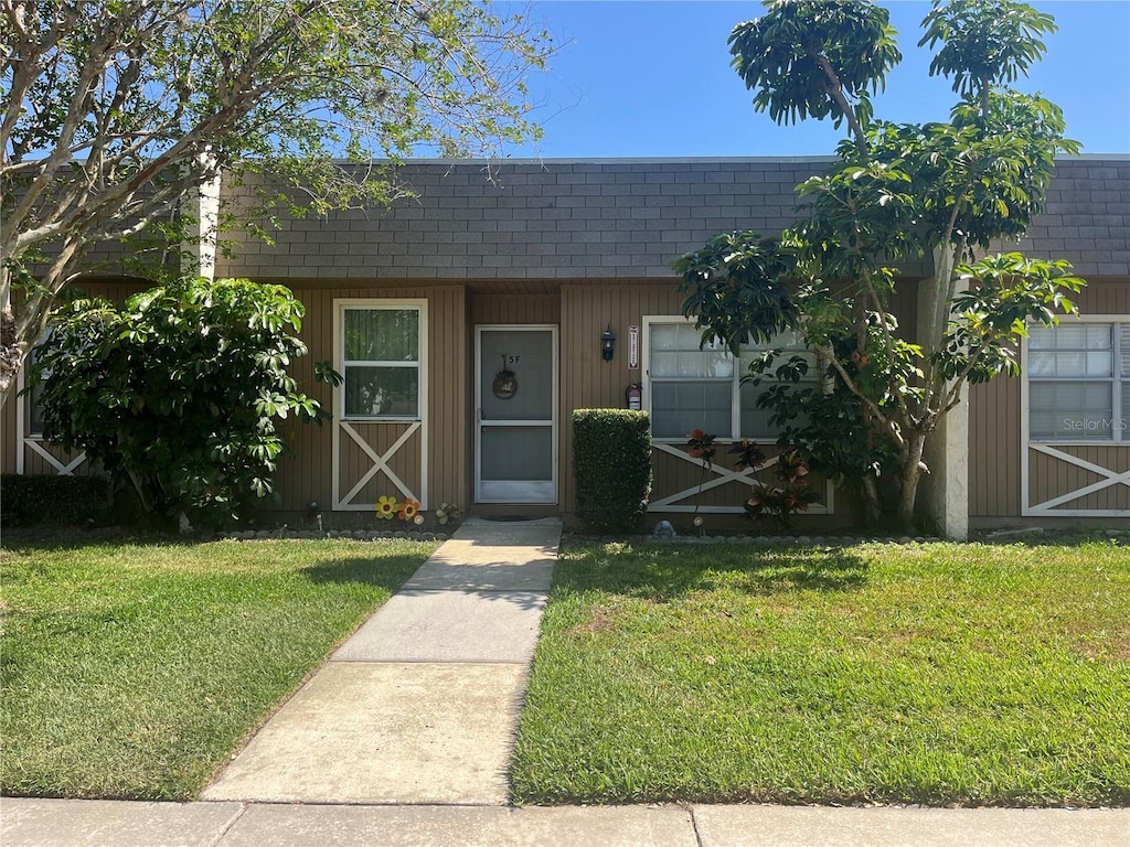 11511 113th St Unit 5C, Largo, FL 33778 - view of property with a shingled roof, a front lawn, and mansard roof