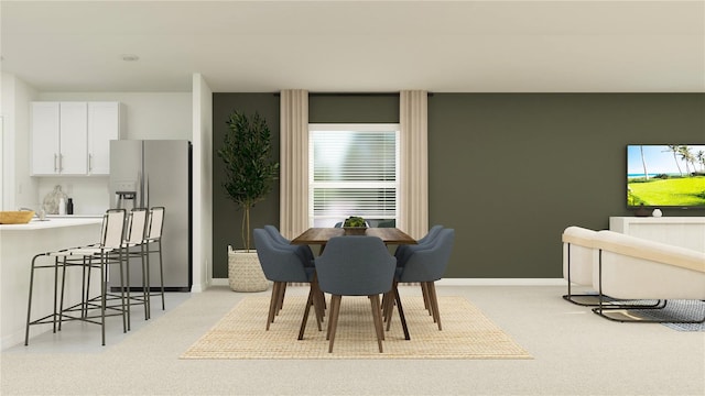 dining room featuring light colored carpet and baseboards