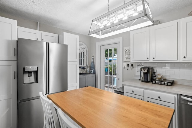 3245 Freemont Ter S, Saint Petersburg, FL 33712 - kitchen with stainless steel appliances, tasteful backsplash, butcher block countertops, white cabinets, and a textured ceiling