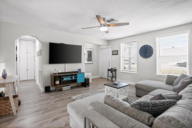 3245 Freemont Ter S, Saint Petersburg, FL 33712 - living area featuring light wood finished floors, ceiling fan, a textured ceiling, baseboards, and arched walkways