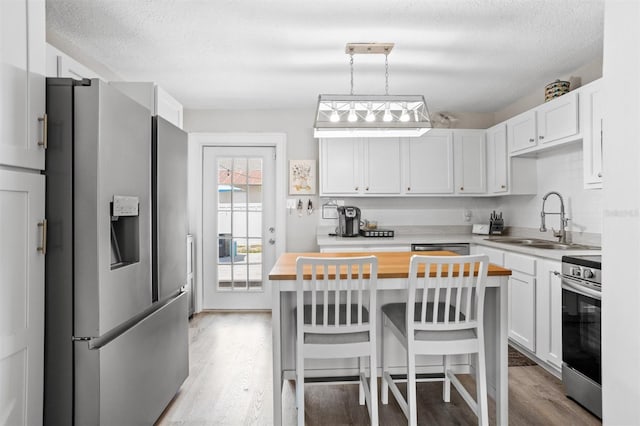 3245 Freemont Ter S, Saint Petersburg, FL 33712 - kitchen with appliances with stainless steel finishes, wood counters, a sink, light wood finished floors, and white cabinets