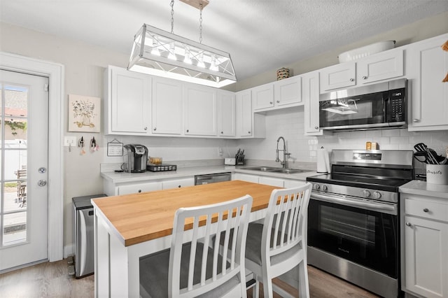 3245 Freemont Ter S, Saint Petersburg, FL 33712 - kitchen with stainless steel appliances, a sink, light wood-style floors, backsplash, and a textured ceiling
