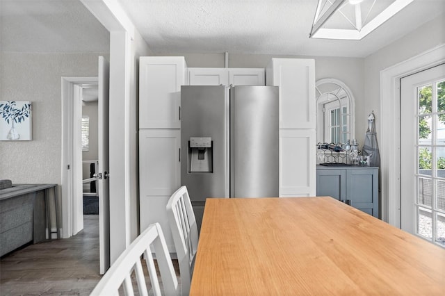 3245 Freemont Ter S, Saint Petersburg, FL 33712 - kitchen with wood finished floors, stainless steel refrigerator with ice dispenser, white cabinetry, wood counters, and a textured ceiling