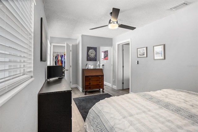 3245 Freemont Ter S, Saint Petersburg, FL 33712 - bedroom featuring a walk in closet, wood finished floors, a textured ceiling, a closet, and ceiling fan