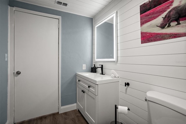 3245 Freemont Ter S, Saint Petersburg, FL 33712 - bathroom featuring wood finished floors, toilet, vanity, wooden walls, and baseboards