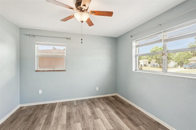 spare room featuring wood finished floors, a ceiling fan, and baseboards