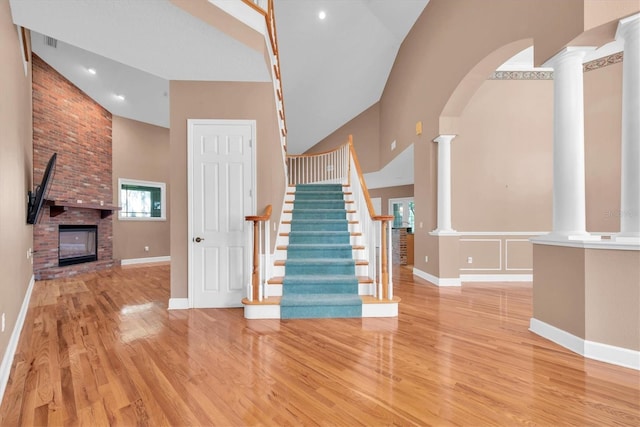 12002 Hope Ln, Tampa, FL 33618 - stairway featuring high vaulted ceiling, ornate columns, wood finished floors, a brick fireplace, and baseboards