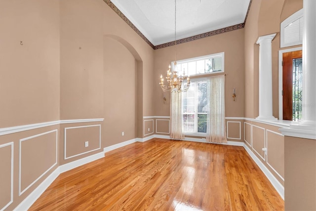 12002 Hope Ln, Tampa, FL 33618 - unfurnished dining area featuring a decorative wall, ornate columns, a chandelier, light wood-type flooring, and wainscoting