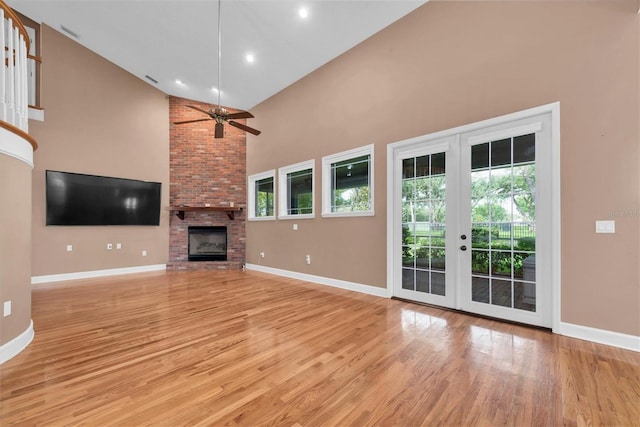 12002 Hope Ln, Tampa, FL 33618 - unfurnished living room featuring high vaulted ceiling, baseboards, light wood finished floors, a fireplace, and french doors