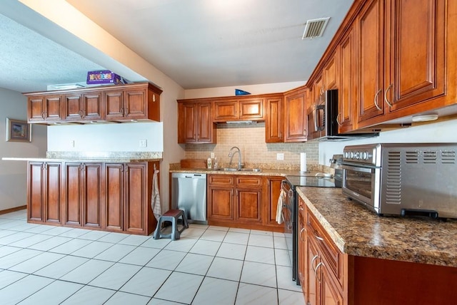 8305 75th Pl, Seminole, FL 33777 - kitchen featuring stainless steel appliances, a sink, brown cabinets, tasteful backsplash, and light tile patterned floors