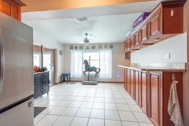 8305 75th Pl, Seminole, FL 33777 - kitchen with freestanding refrigerator, light countertops, baseboards, brown cabinetry, and a textured ceiling