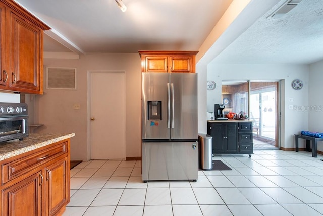 8305 75th Pl, Seminole, FL 33777 - kitchen featuring stainless steel fridge with ice dispenser, brown cabinetry, light tile patterned flooring, and light stone countertops