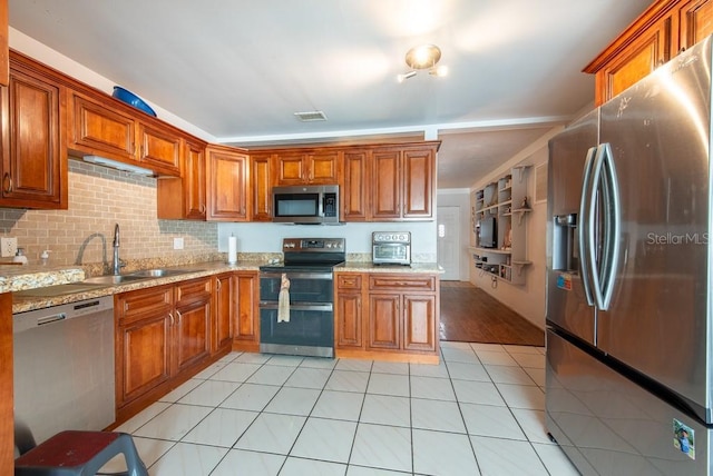 8305 75th Pl, Seminole, FL 33777 - kitchen with appliances with stainless steel finishes, a sink, brown cabinetry, light stone counters, and light tile patterned floors