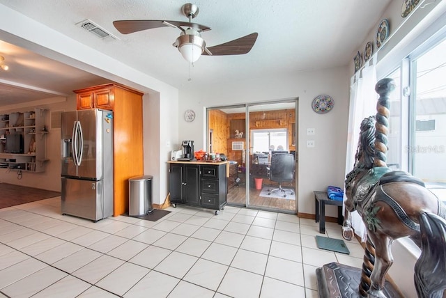 8305 75th Pl, Seminole, FL 33777 - kitchen featuring stainless steel fridge, ceiling fan, brown cabinets, open floor plan, and light tile patterned flooring