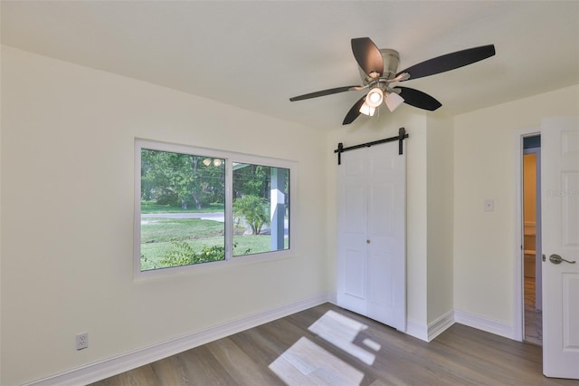 10922 Park Dr, Riverview, FL 33569 - unfurnished bedroom featuring wood finished floors, a barn door, and a ceiling fan
