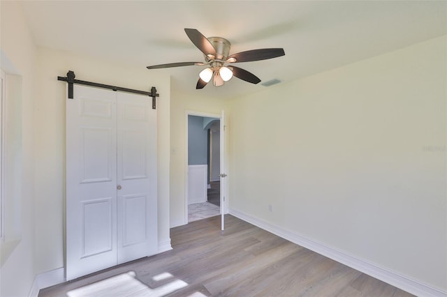 10922 Park Dr, Riverview, FL 33569 - unfurnished bedroom with a barn door, light wood-style floors, a closet, and a ceiling fan