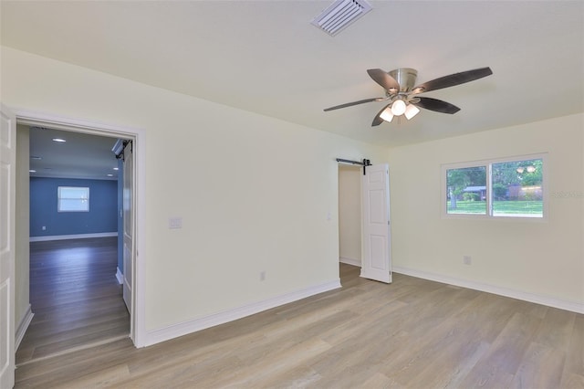 10922 Park Dr, Riverview, FL 33569 - spare room with light wood finished floors, a barn door, and a ceiling fan