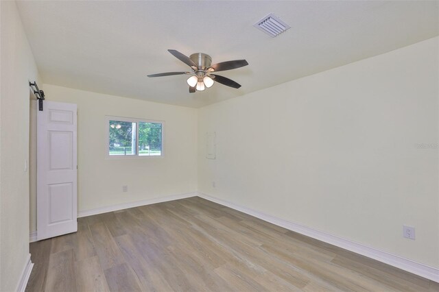 10922 Park Dr, Riverview, FL 33569 - spare room featuring a barn door, wood finished floors, and ceiling fan