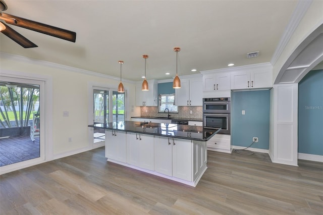 10922 Park Dr, Riverview, FL 33569 - kitchen featuring dark countertops, white cabinets, wood finished floors, stainless steel double oven, and decorative backsplash