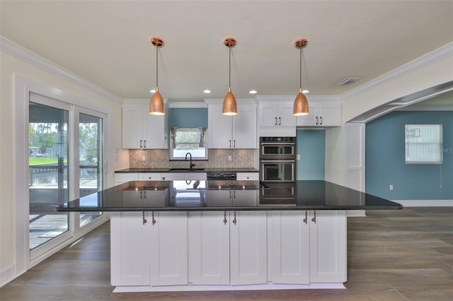 10922 Park Dr, Riverview, FL 33569 - kitchen with white cabinets, black appliances, decorative backsplash, a center island, and crown molding