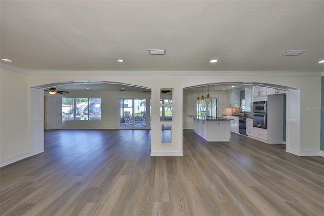 10922 Park Dr, Riverview, FL 33569 - unfurnished living room featuring crown molding, a ceiling fan, dark wood-style flooring, arched walkways, and recessed lighting