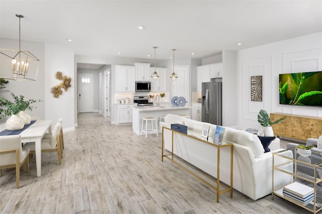 living room featuring a chandelier, light wood-style floors, recessed lighting, and baseboards