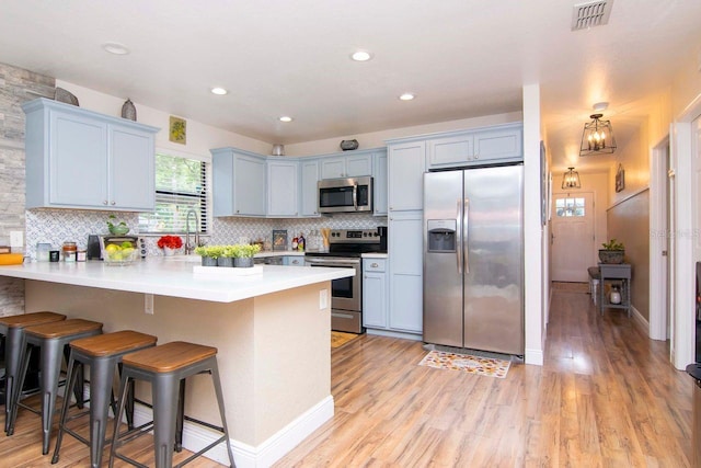 351 Hancock St, Dunedin, FL 34698 - kitchen featuring stainless steel appliances, a peninsula, a breakfast bar, tasteful backsplash, and light wood-style floors
