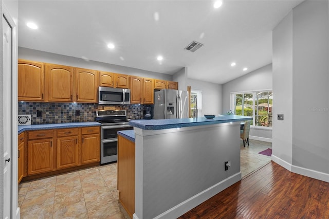 18631 Le Dauphine Pl, Lutz, FL 33558 - kitchen featuring appliances with stainless steel finishes, dark countertops, baseboards, decorative backsplash, and a kitchen island