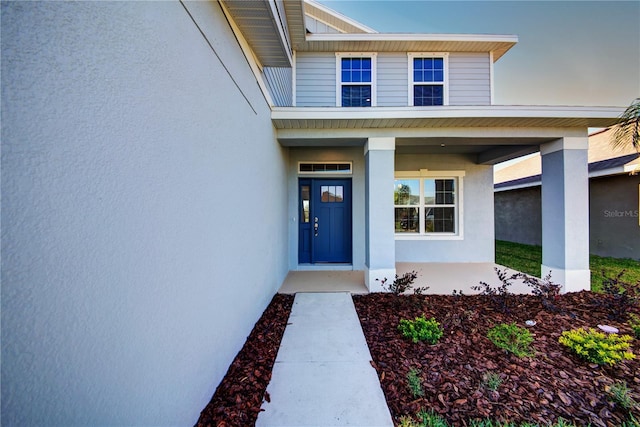 doorway to property with stucco siding and a porch